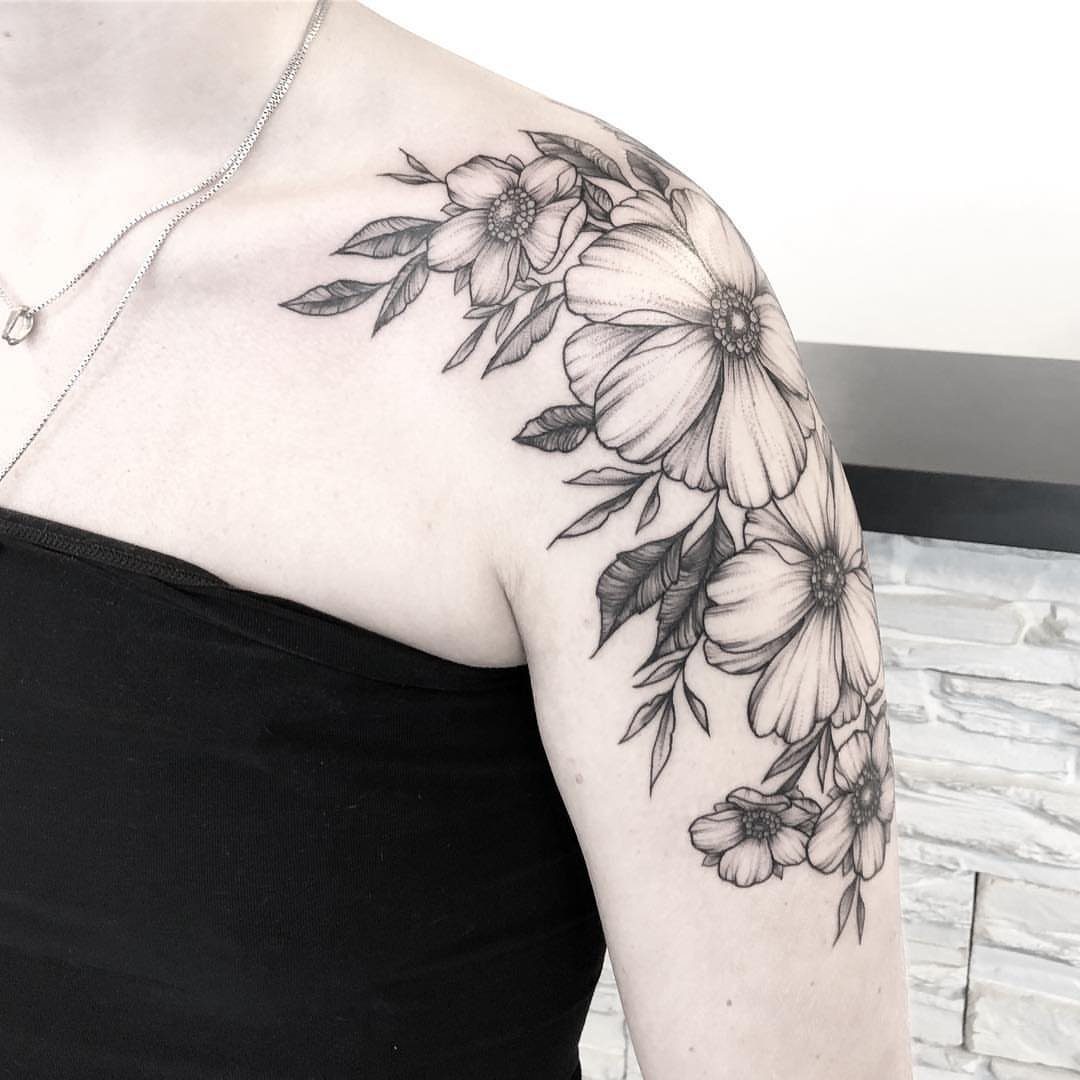 Floral tattoo with flowers and leaves cascading down a person's shoulder and arm.