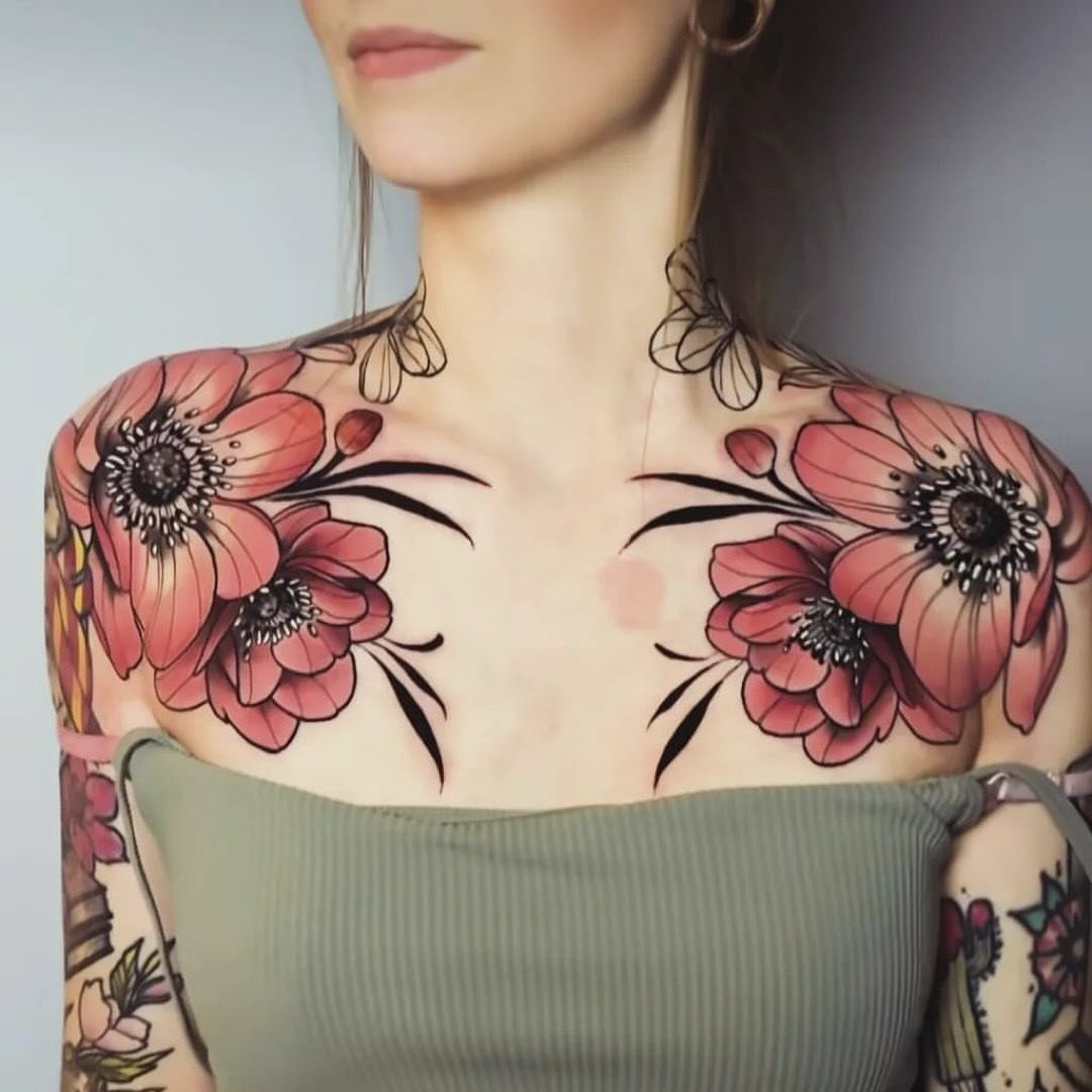 Red floral tattoos on the shoulders and collarbones of a woman.