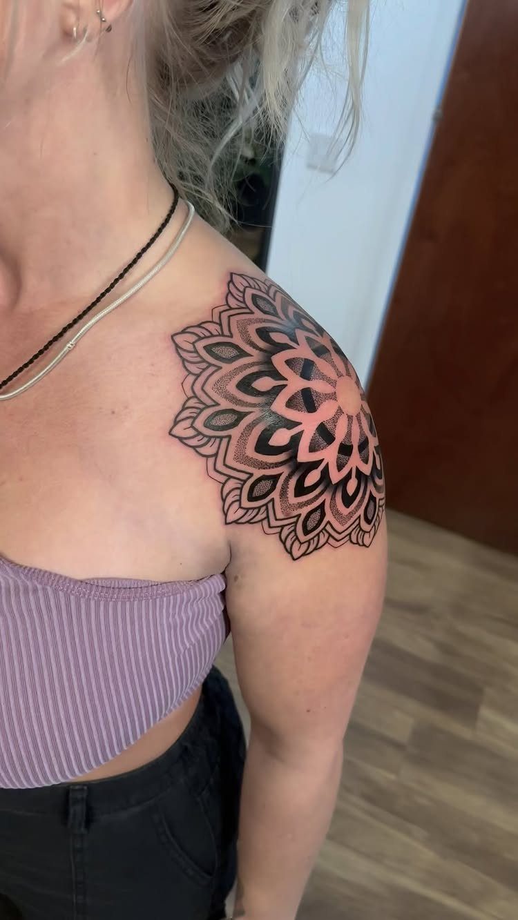Mandala tattoo on a person's shoulder with detailed black ink geometric patterns.