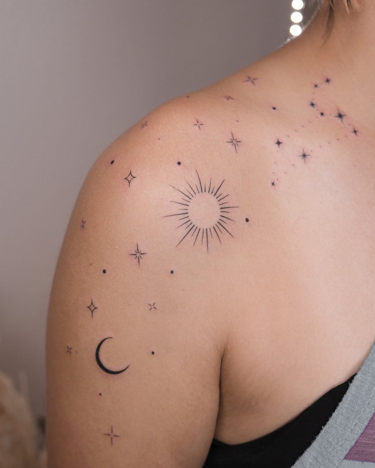 Sun and crescent moon tattoos with stars on a person's shoulder