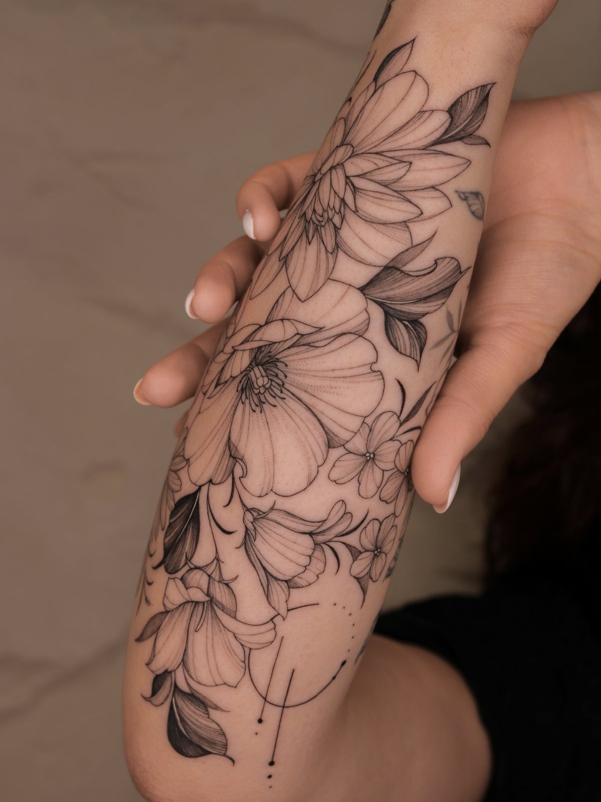 Floral fine line tattoo on a forearm featuring large blooming flowers and leaves.