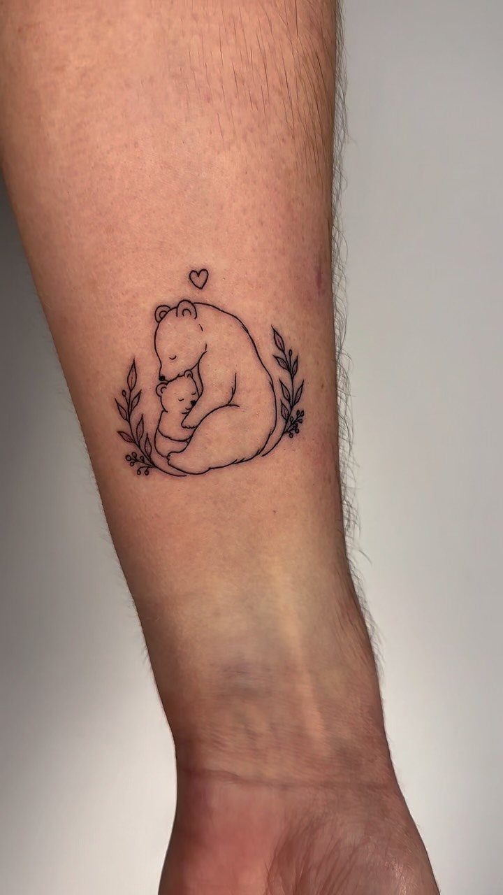 Fine line tattoo of a bear hugging a cub on a forearm.