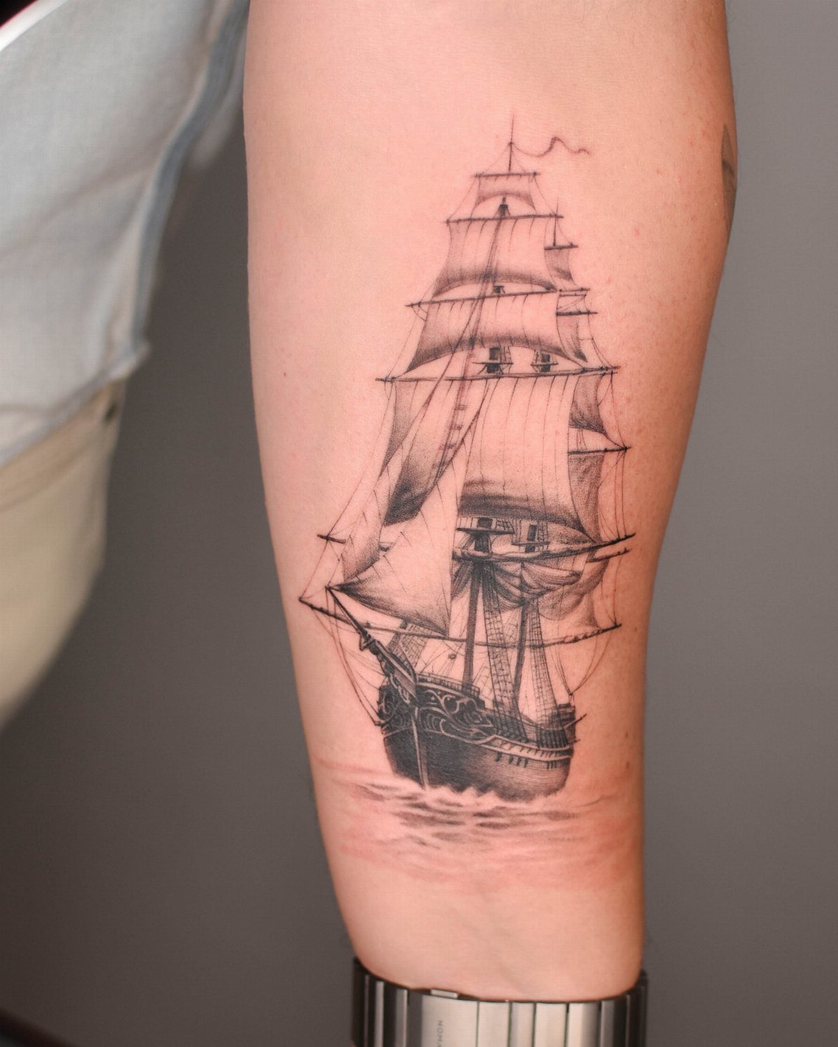 Fine line tattoo of a detailed sailing ship on a man's forearm