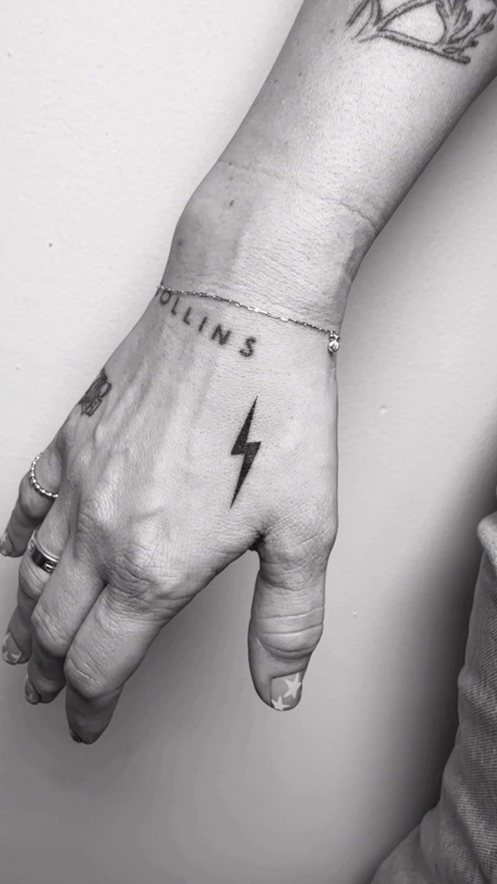 Small black lightning bolt tattoo on the back of a person's hand.