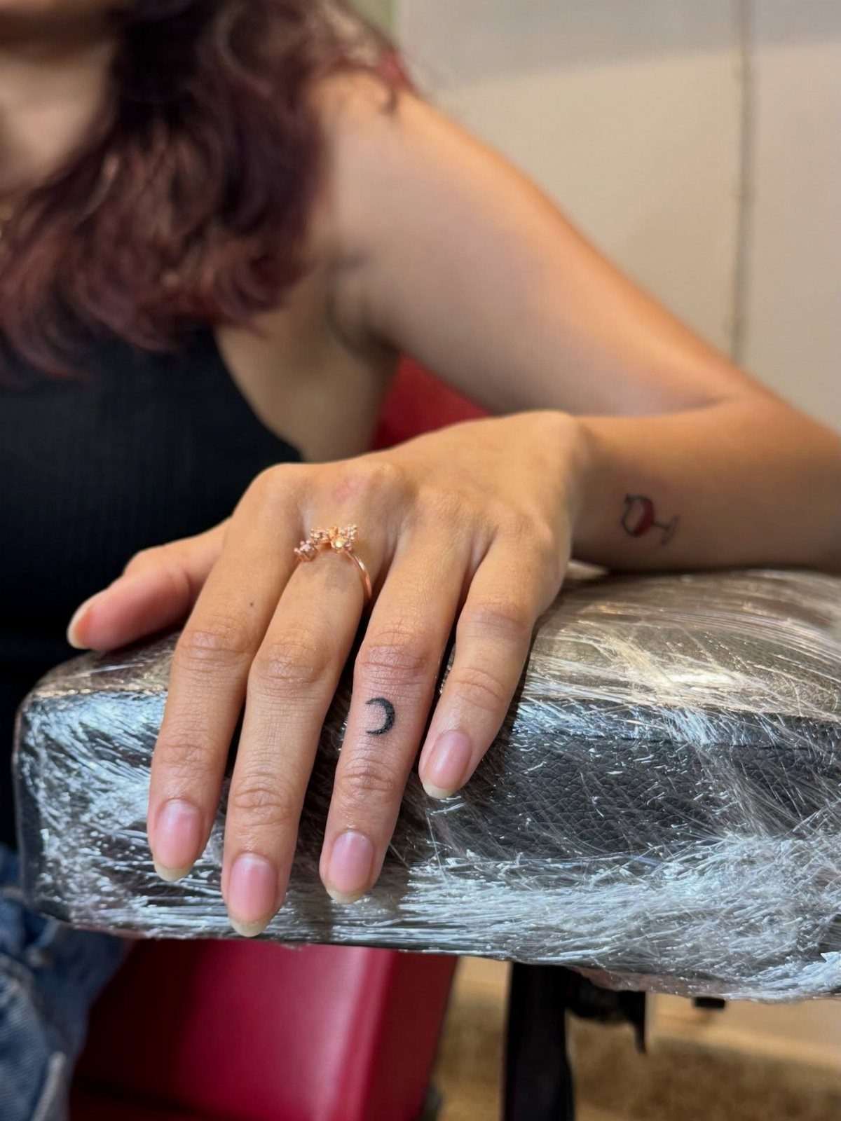 Crescent moon tattoo on a middle finger and wine glass tattoo on wrist.