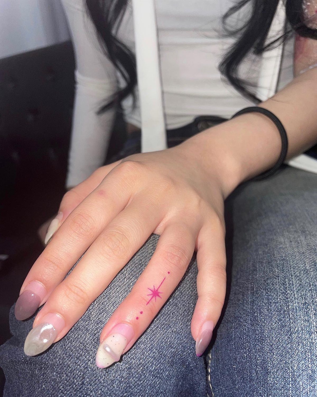 Woman's hand with a small pink star tattoo on her ring finger.