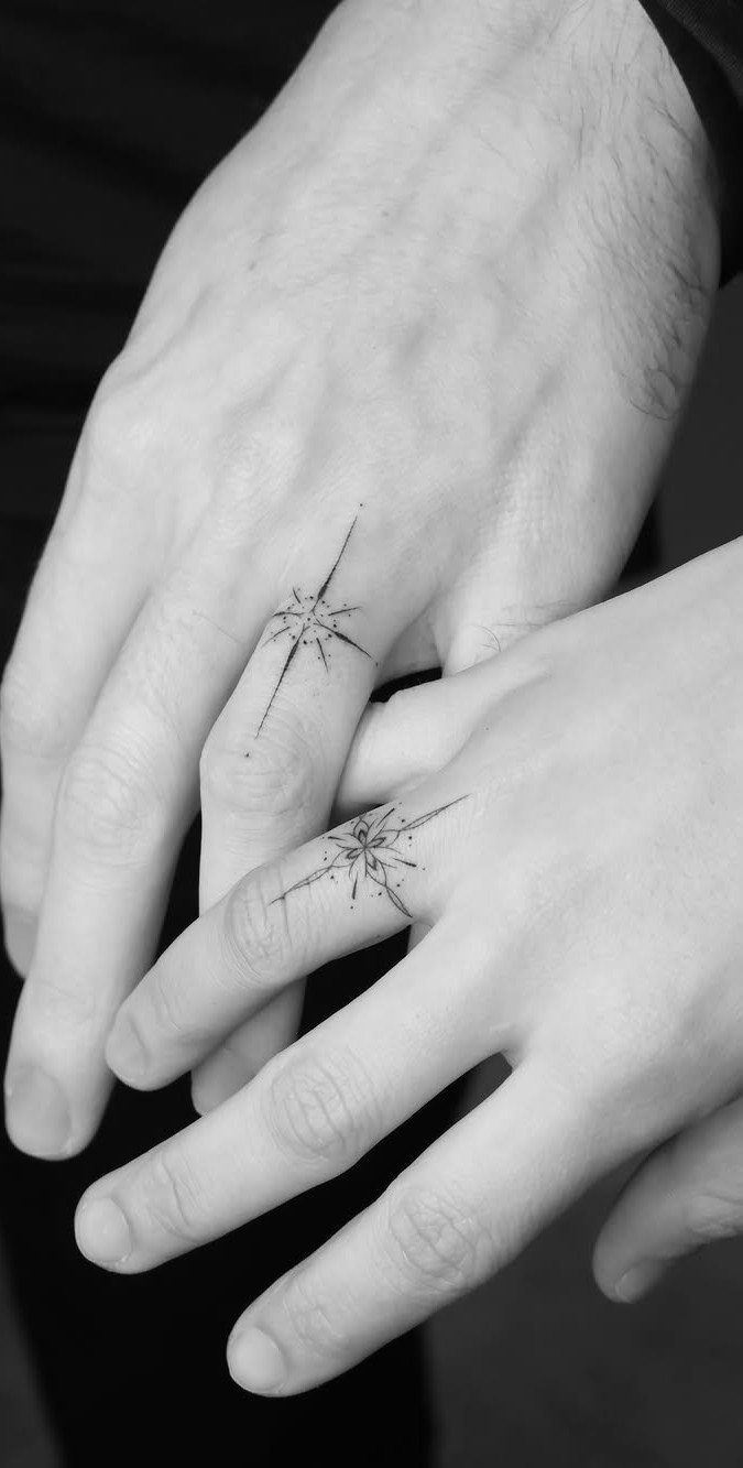 Two hands with matching sparkle tattoos on the fingers in black and white.