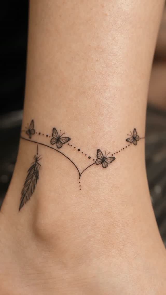 Ankle tattoo featuring a delicate line with butterflies and a hanging feather.