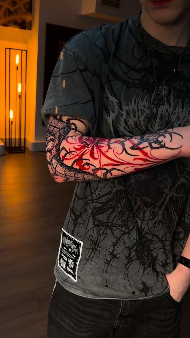 Forearm tattoo with red and black abstract swirling patterns on a person.