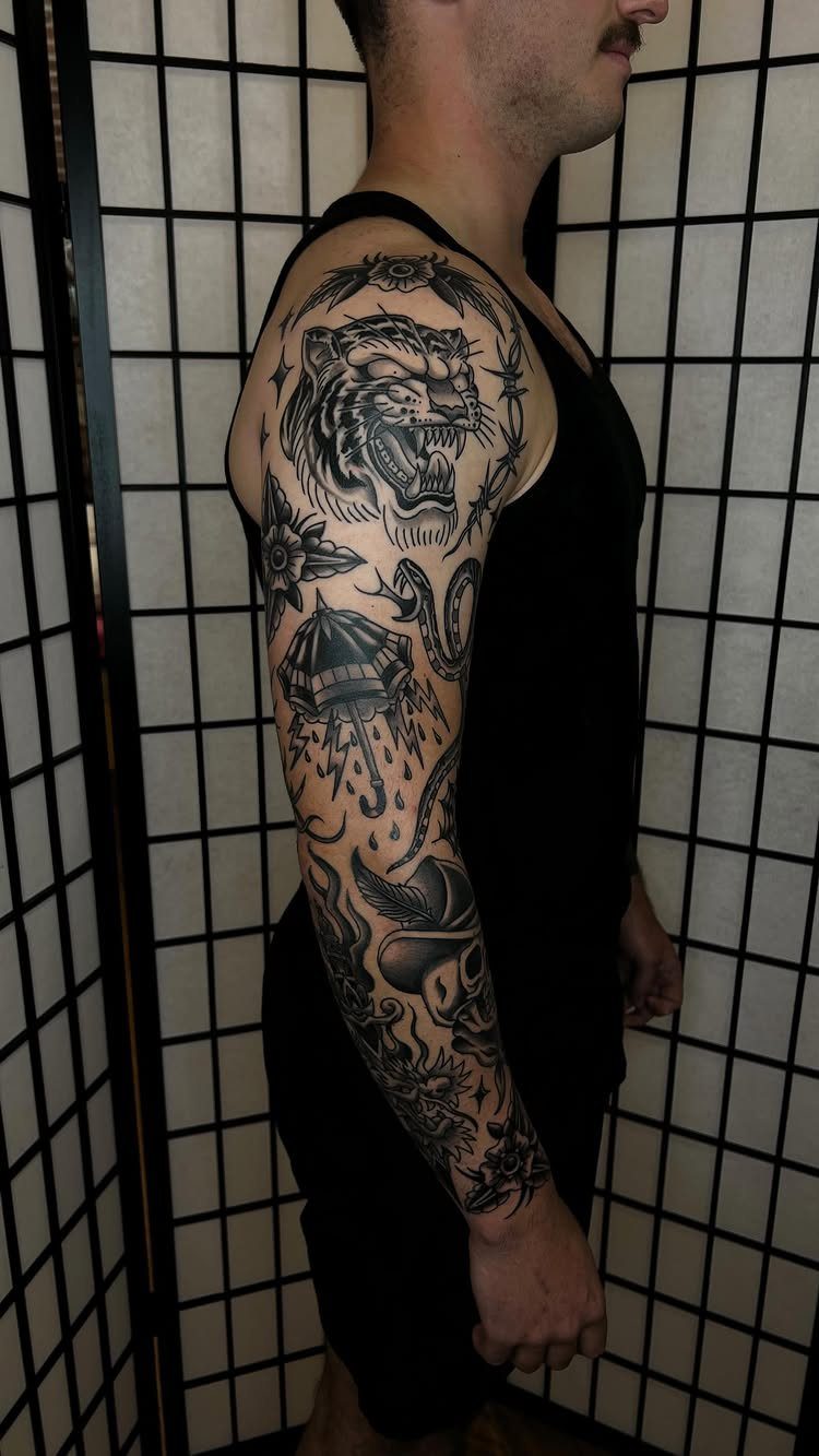 Full sleeve tattoo on a man's arm featuring a tiger and umbrella designs.