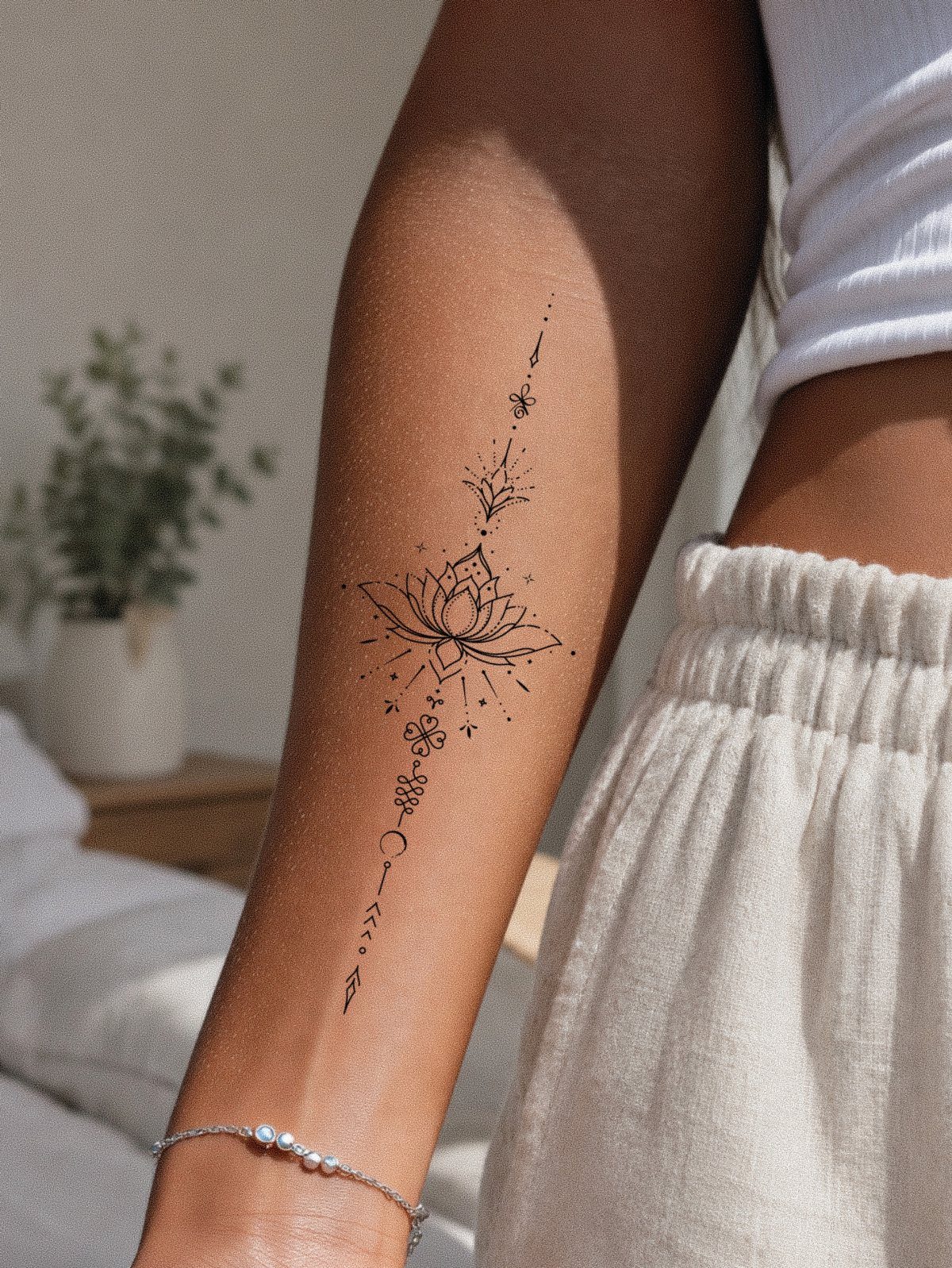 Lotus flower tattoo with geometric details on a person's forearm