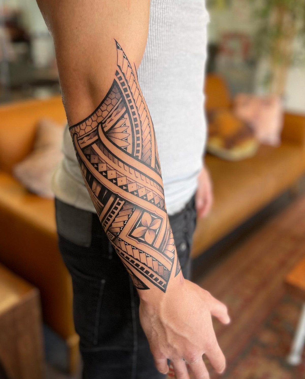 Man's forearm with a detailed black ink Polynesian tribal tattoo and geometric patterns.