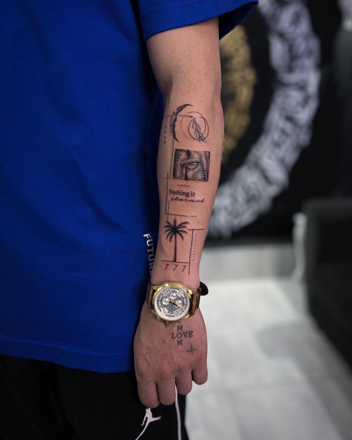 Man's forearm with multiple small black ink tattoos and a gold watch.