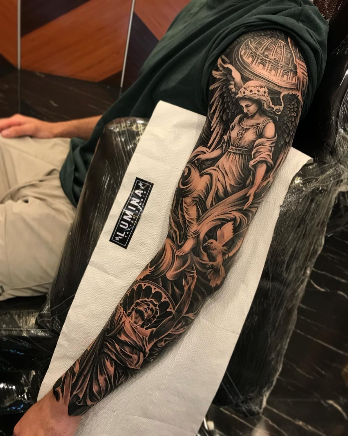 Full sleeve tattoo of a winged angel on a man's arm.