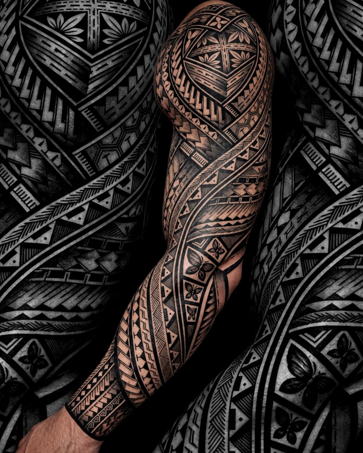 Full sleeve tribal tattoo on a man's arm with bold black geometric patterns.