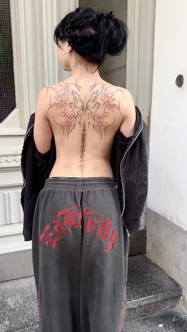 Woman with a large floral tattoo covering her upper back and spine.