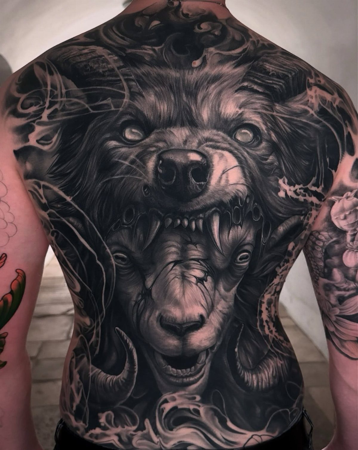 Wolf and ram head tattoo covering the full back in black and grey ink.