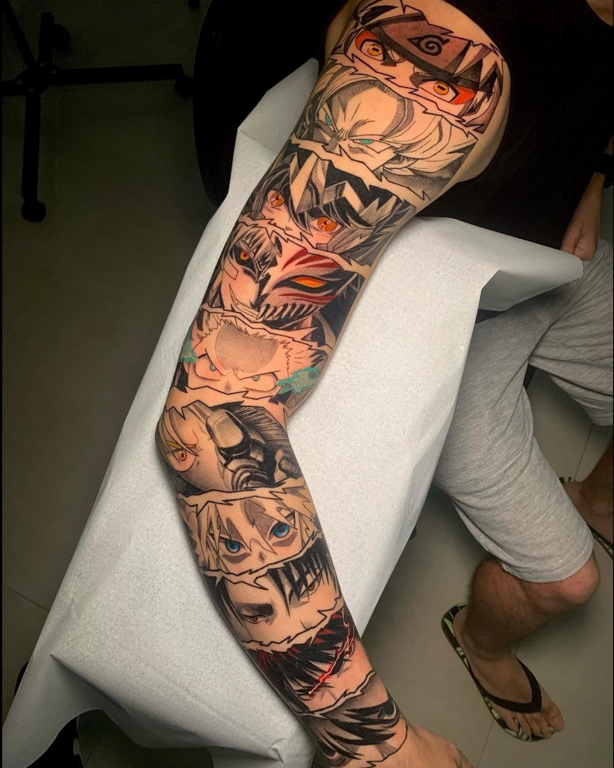 Full sleeve tattoo on a man's arm featuring various anime character portraits.