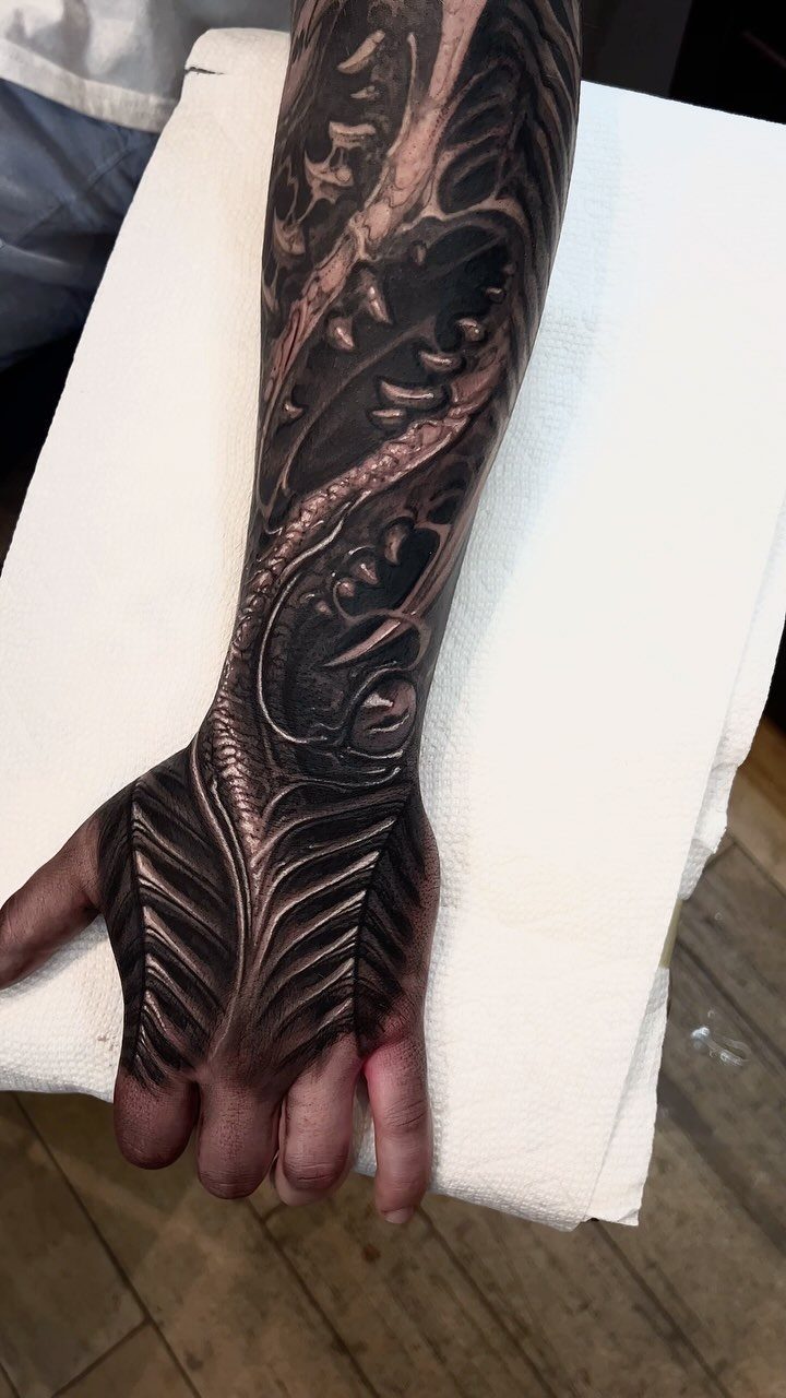 Biomechanical sleeve tattoo on a man's arm and hand with intricate mechanical details.