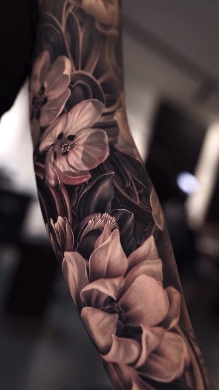 Detailed floral sleeve tattoo with large blossoms and leaves on a man's arm