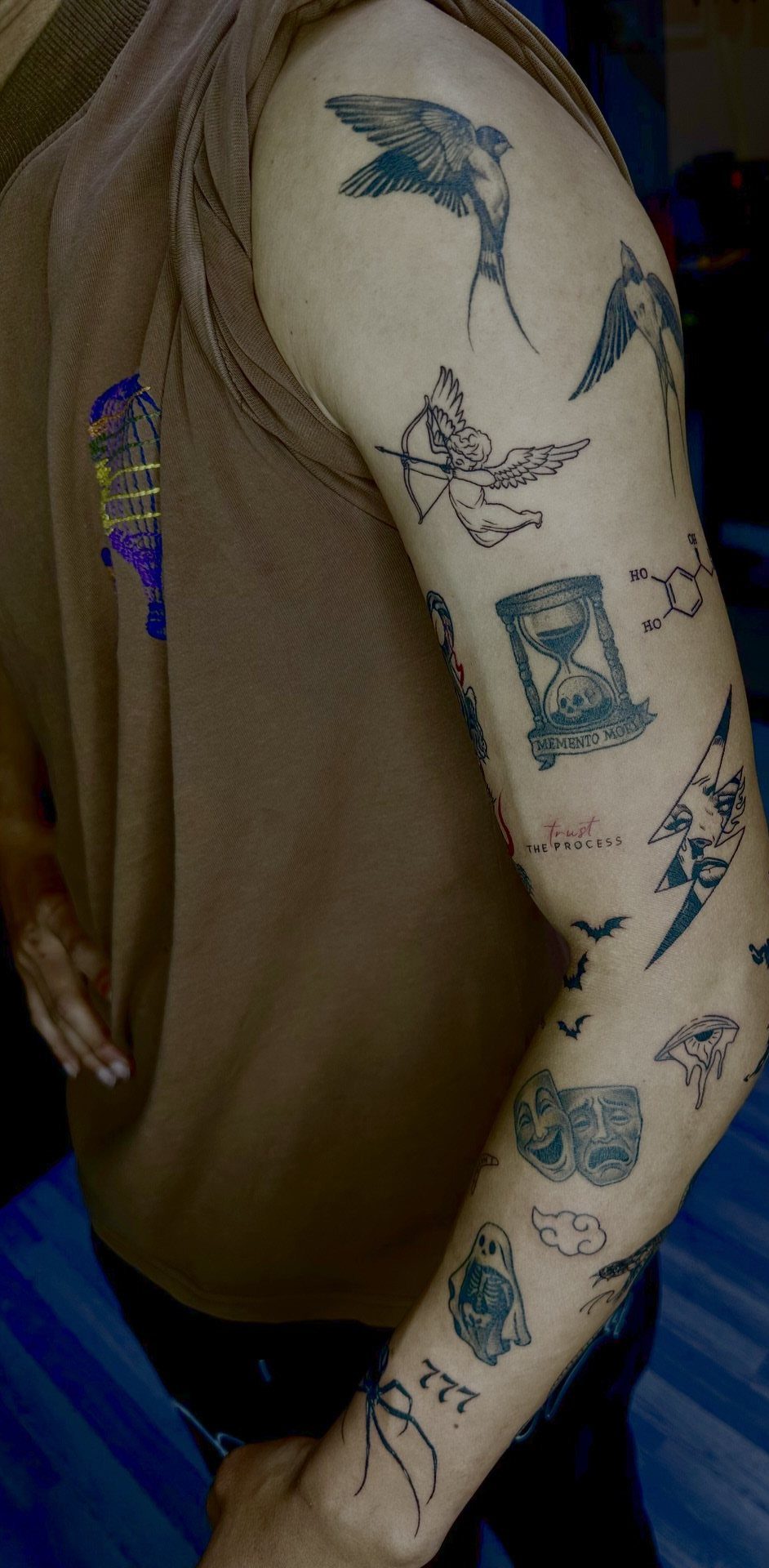 Man's arm with a patchwork sleeve tattoo featuring various small black ink symbols.