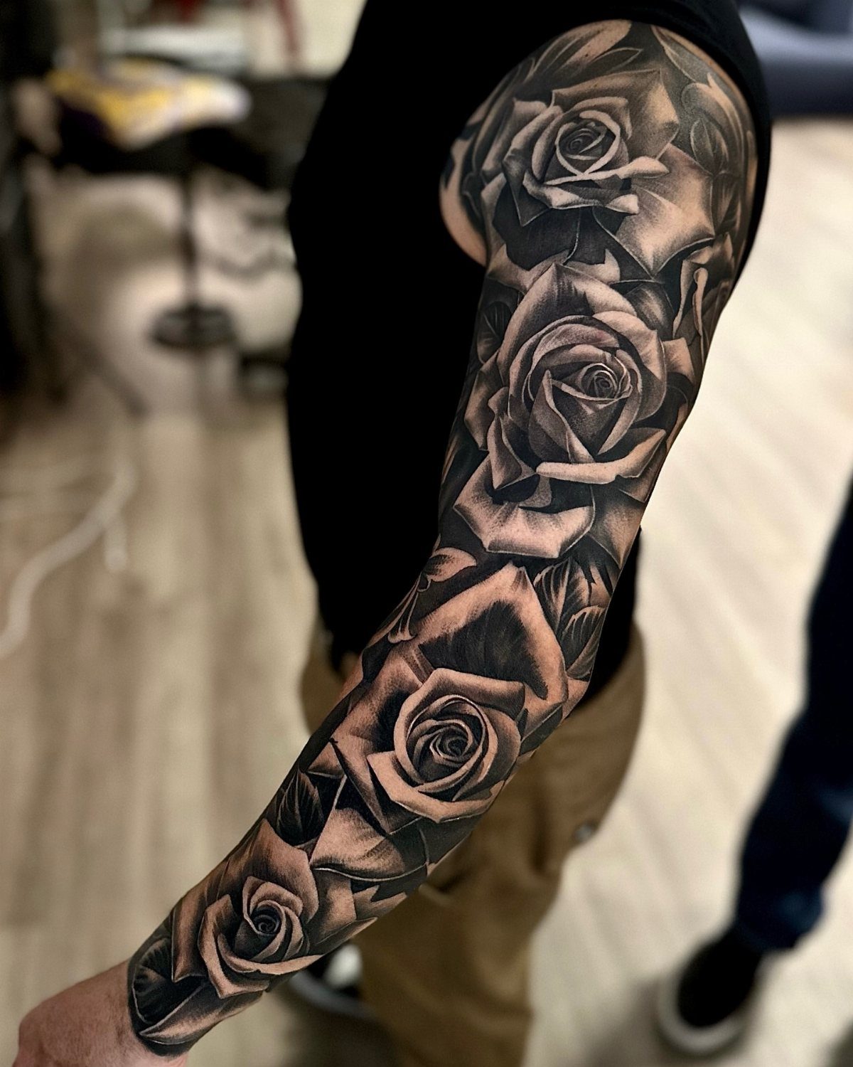 Full sleeve tattoo of black and grey roses on a man's arm