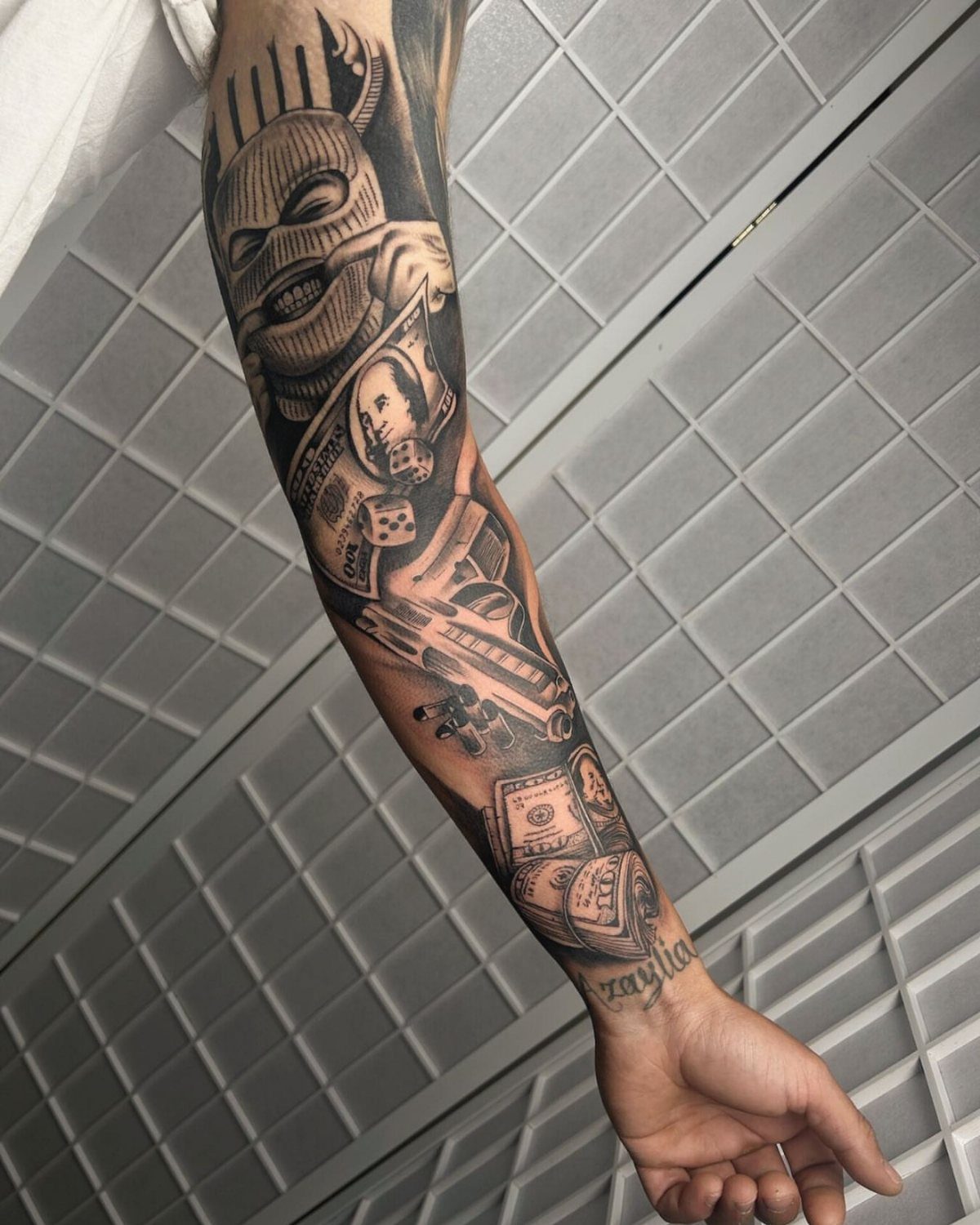 Full sleeve tattoo with money and masked figure wrapping around a person's arm.