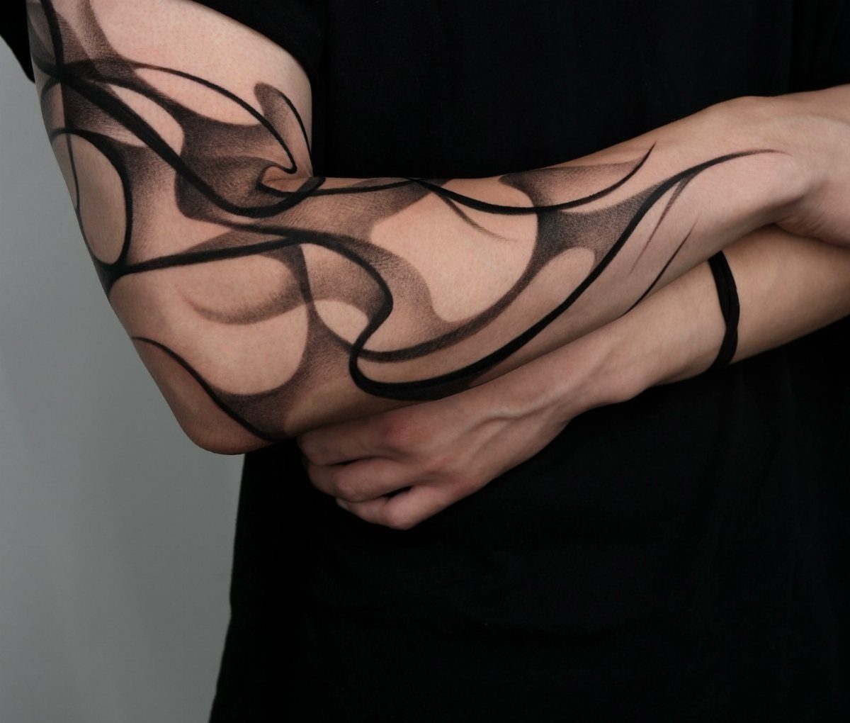 Abstract black ink tattoo with flowing curves wrapping around a person's arm