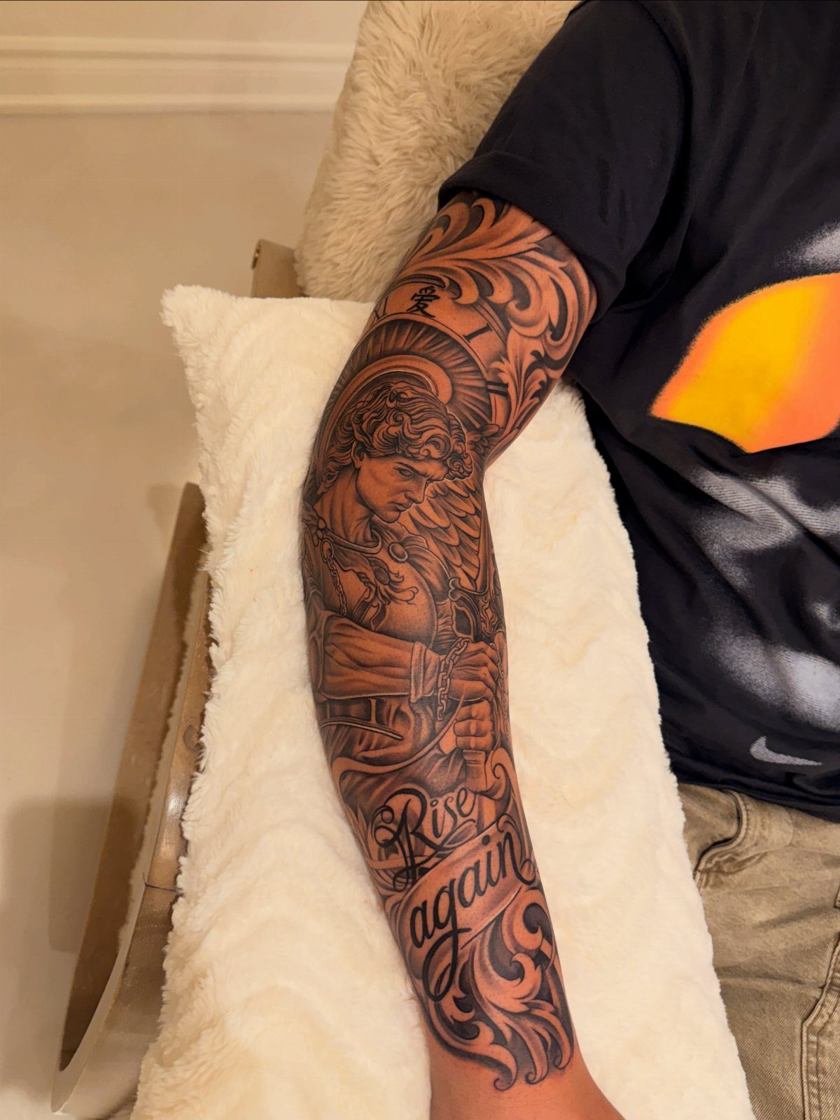Full sleeve tattoo on an arm featuring a portrait and the words Rise again.