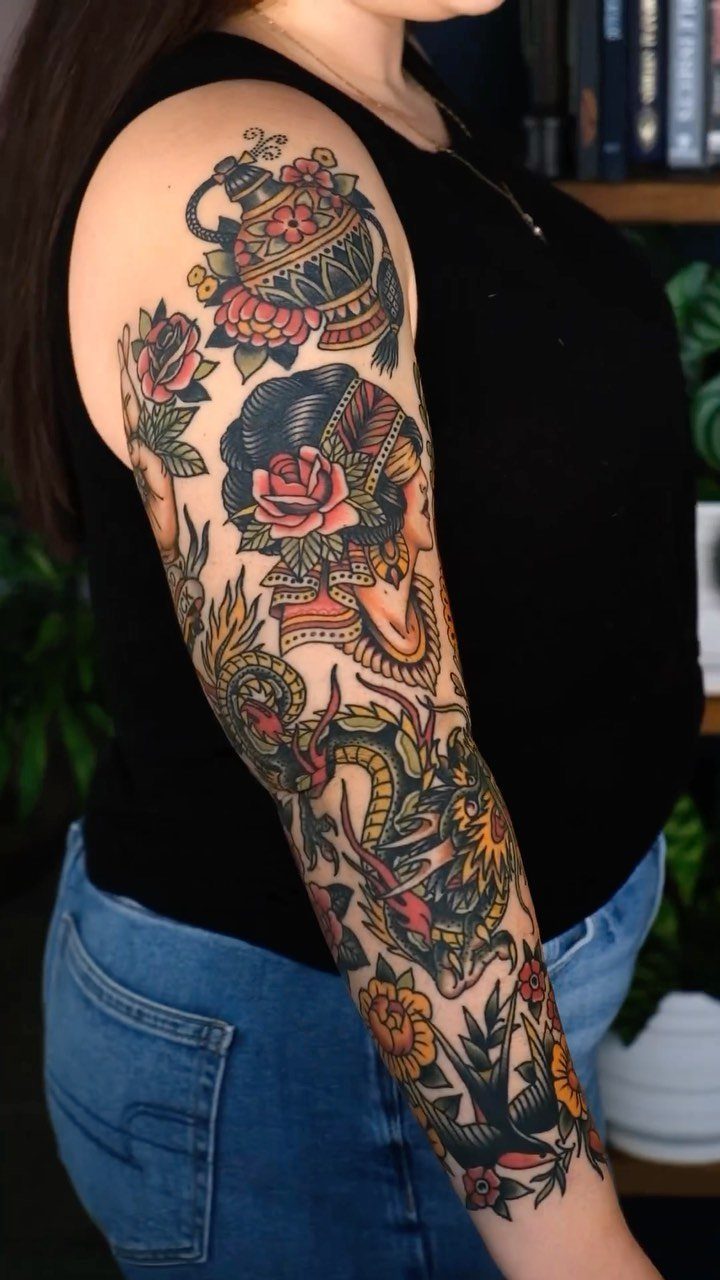 Full sleeve tattoo with traditional bold lines, featuring a woman, flowers, and a vase.
