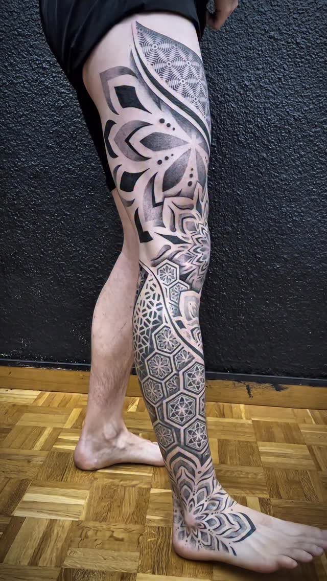 Man's leg with a full geometric and mandala tattoo from thigh to foot.