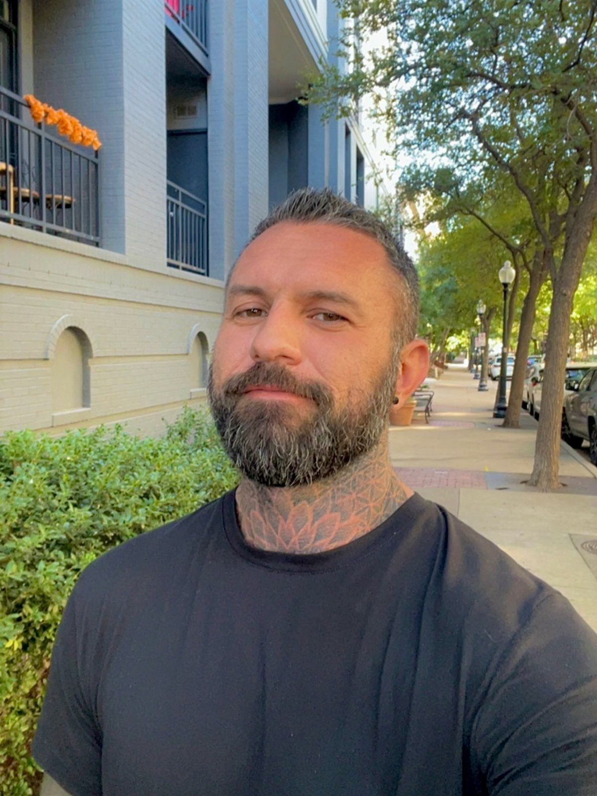 Man with a beard and a geometric mandala tattoo on his neck.