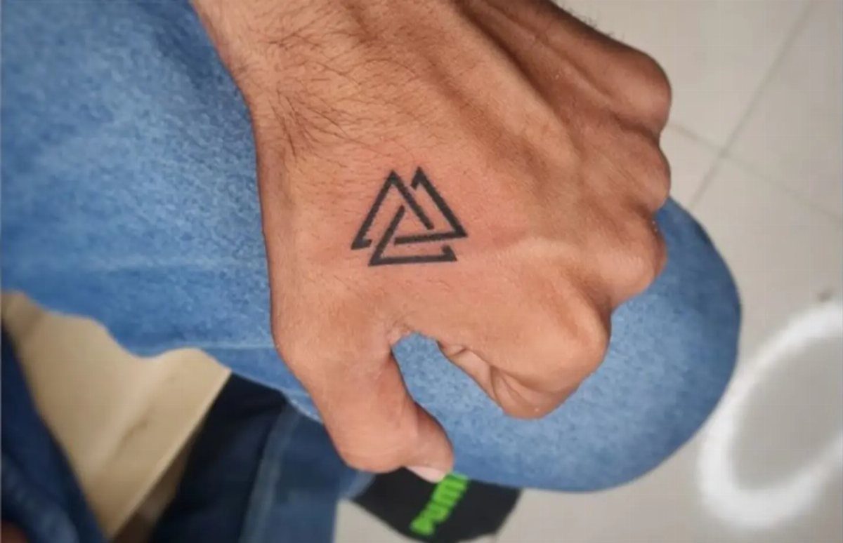 Geometric tattoo of three interlocking triangles on the back of a man's hand.