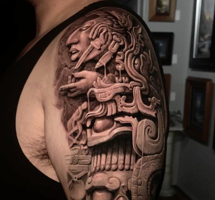 Half sleeve tattoo on an arm featuring detailed Mayan stone carving artwork.