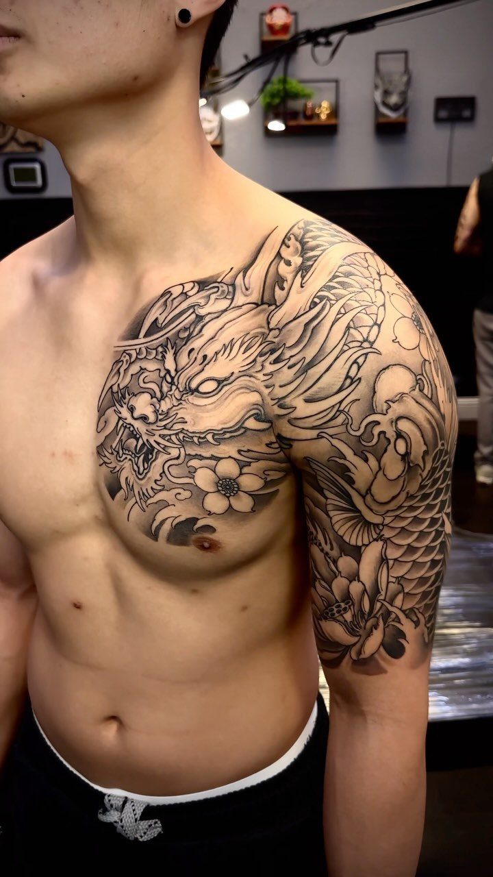 Man with a black and grey dragon half sleeve tattoo on his arm and chest