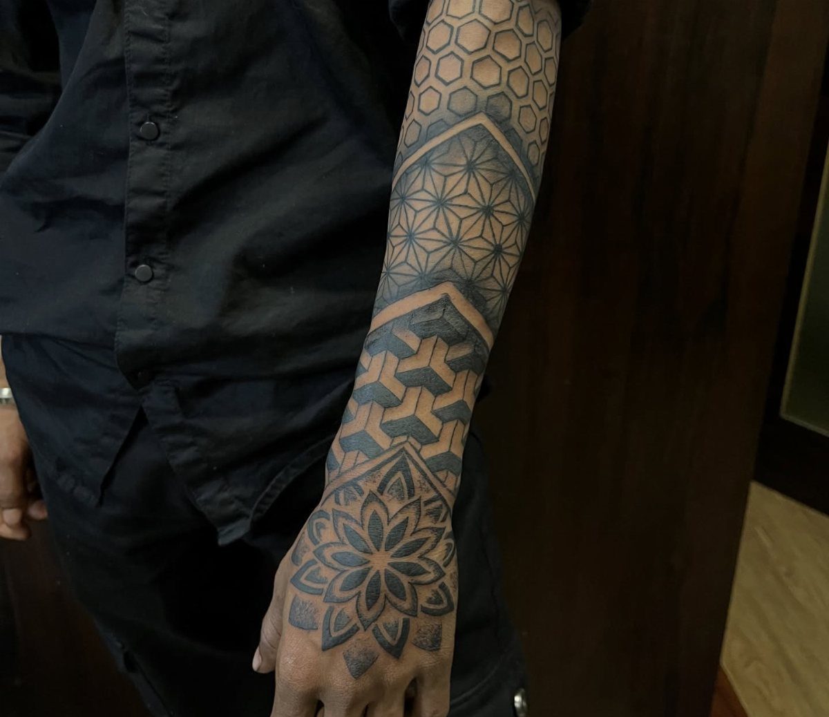 Geometric half sleeve tattoo with honeycombs and a mandala on a person's arm