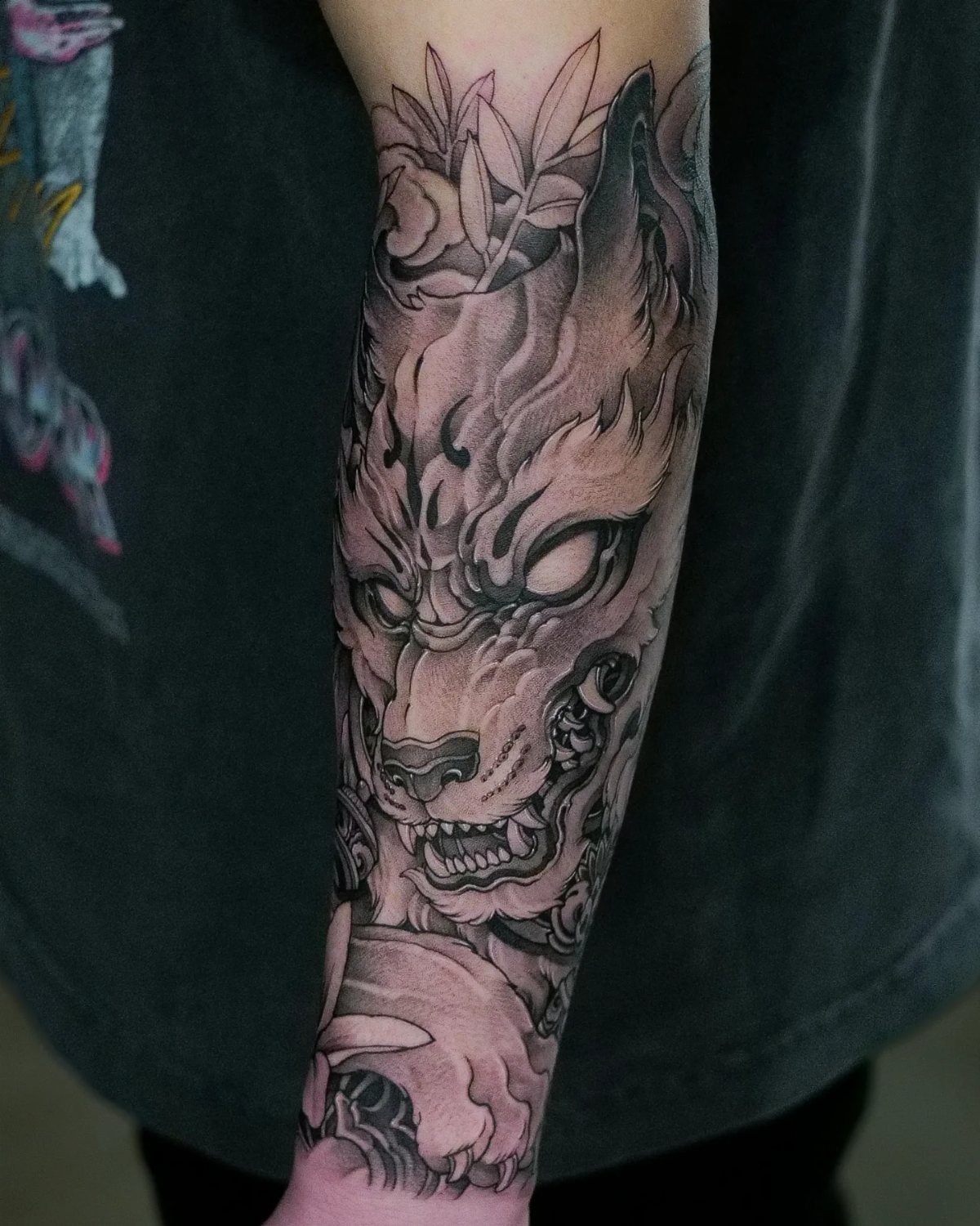 Wolf head illustrative half sleeve tattoo in black and grey on a forearm