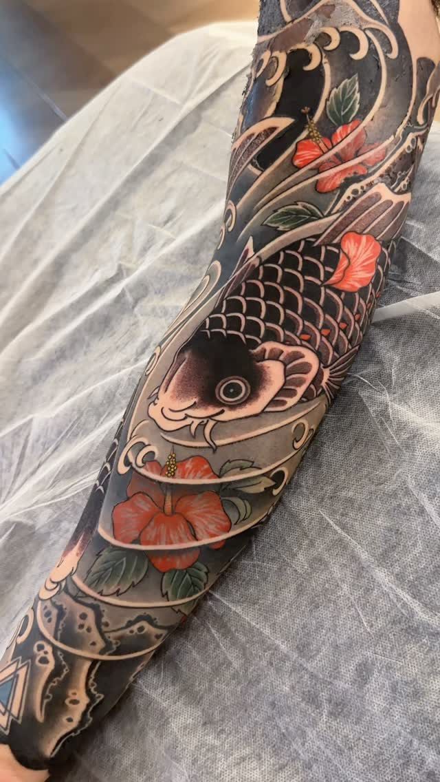 Koi fish half sleeve tattoo with red hibiscus flowers and grey water waves.