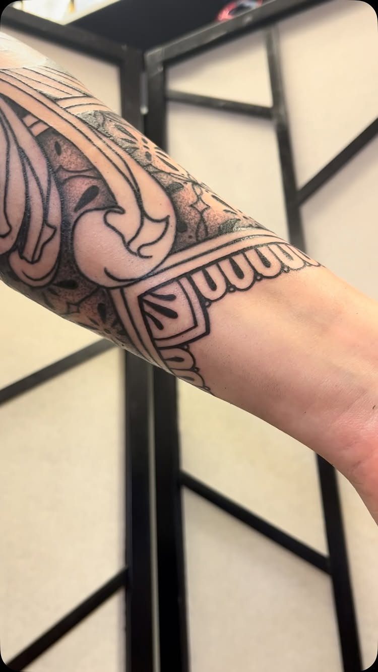 Ornamental blackwork pattern tattoo on a person's arm with bold geometric designs.
