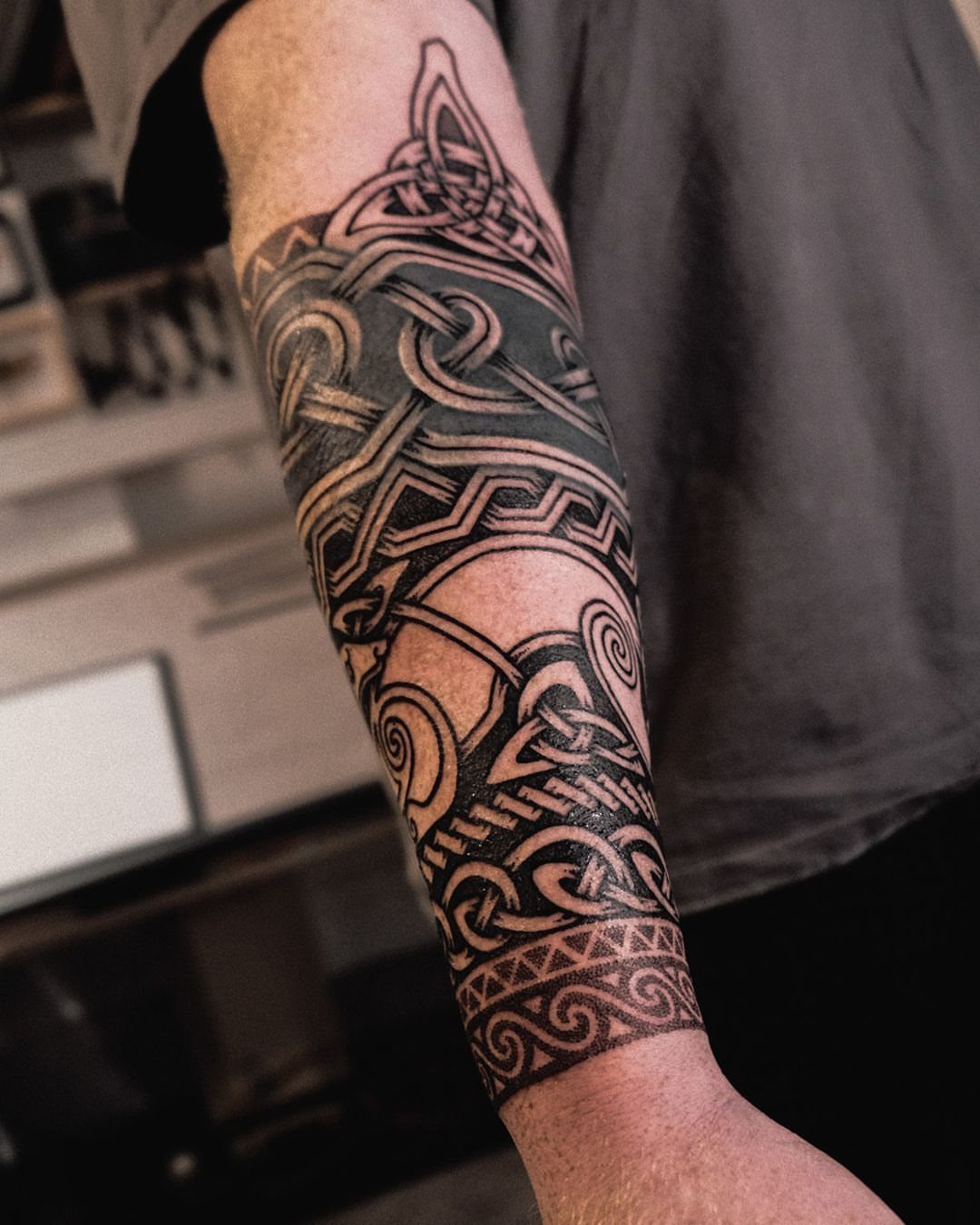 Celtic knotwork half sleeve tattoo on a man's arm with black ink patterns.