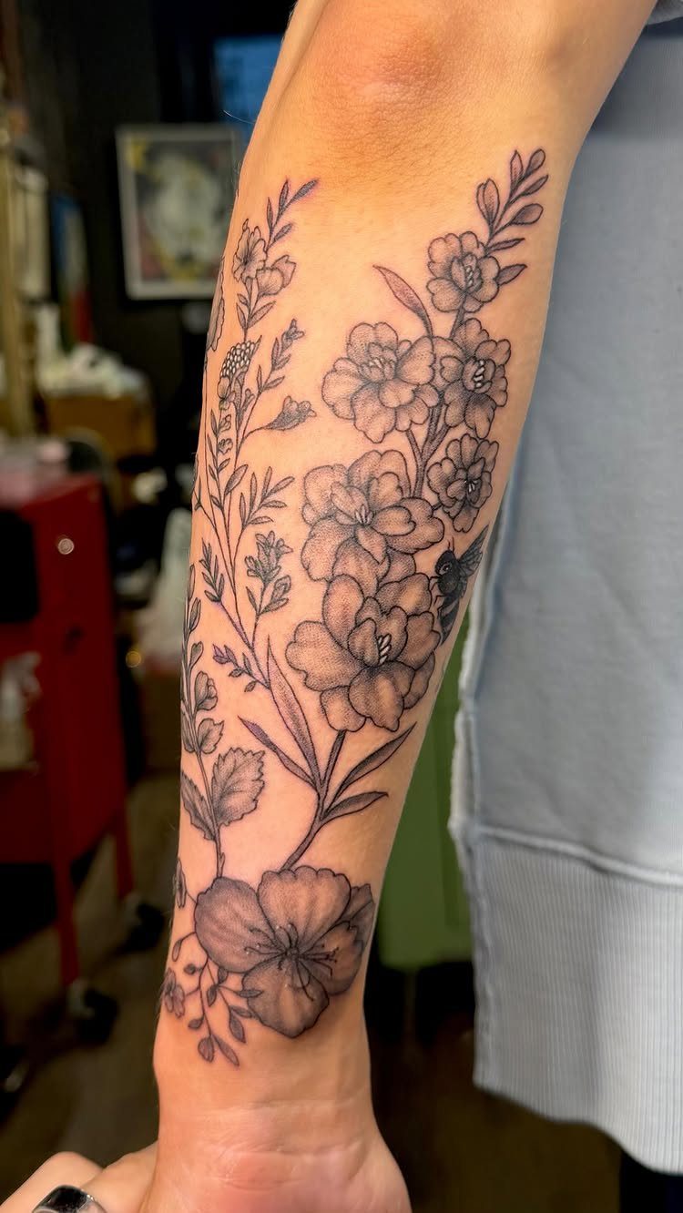 Floral half sleeve tattoo with black ink botanical illustrations on a man's forearm