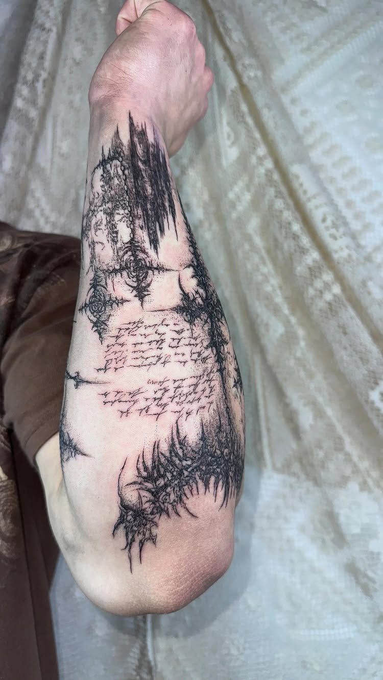 Forearm with a detailed black ink gothic tattoo featuring architecture and script text.