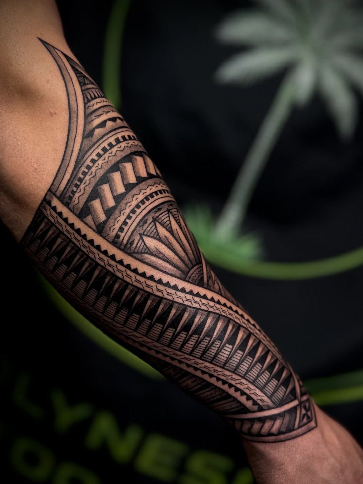 Forearm tattoo with intricate black geometric patterns and tribal motifs on skin.
