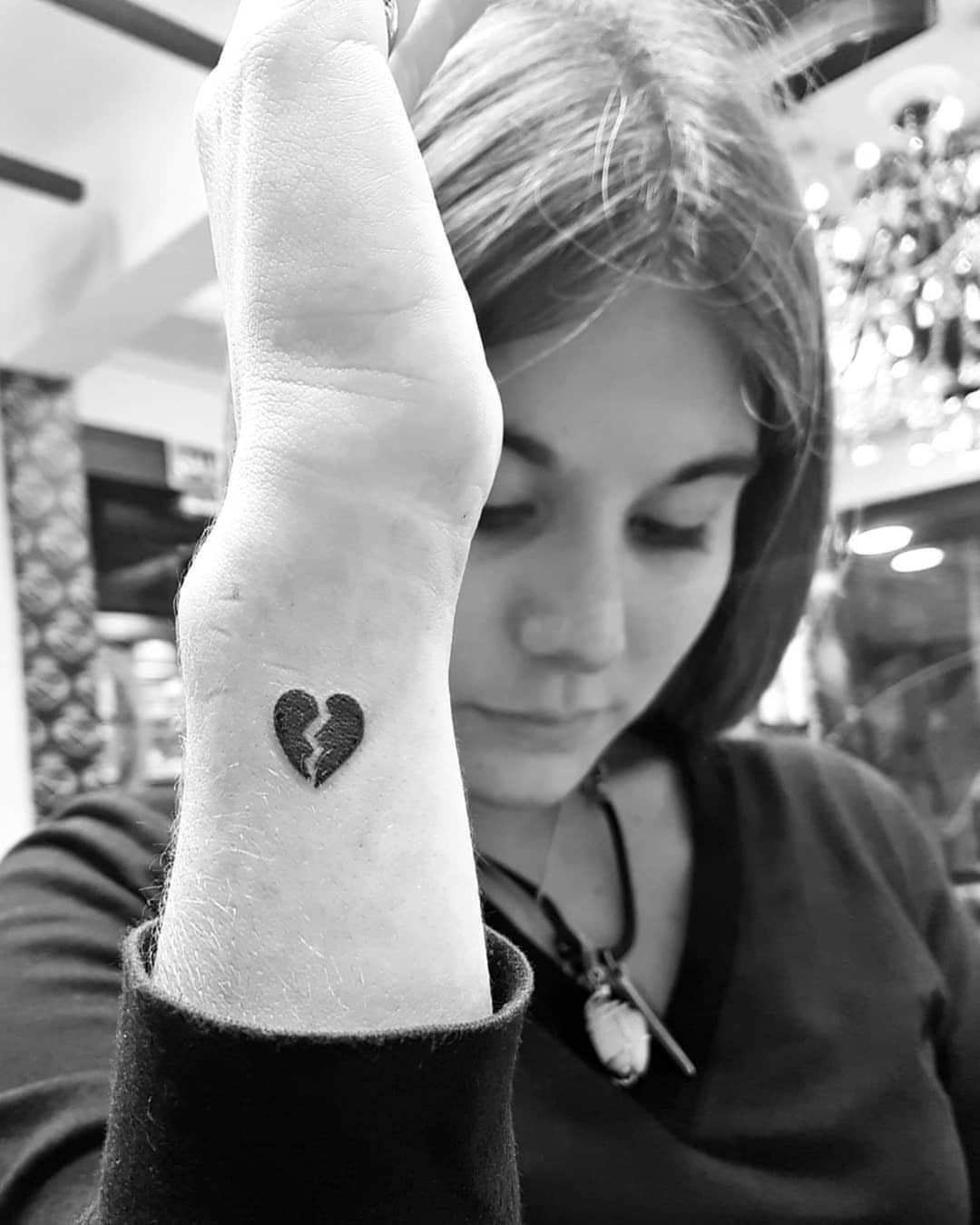 Broken heart tattoo on a woman's wrist in a black and white photograph