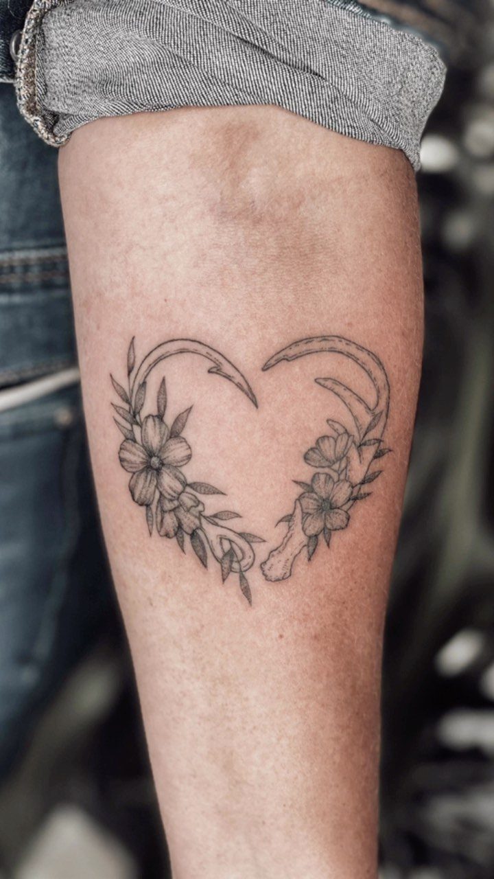 Heart tattoo with flowers and leaves on a person's lower leg.