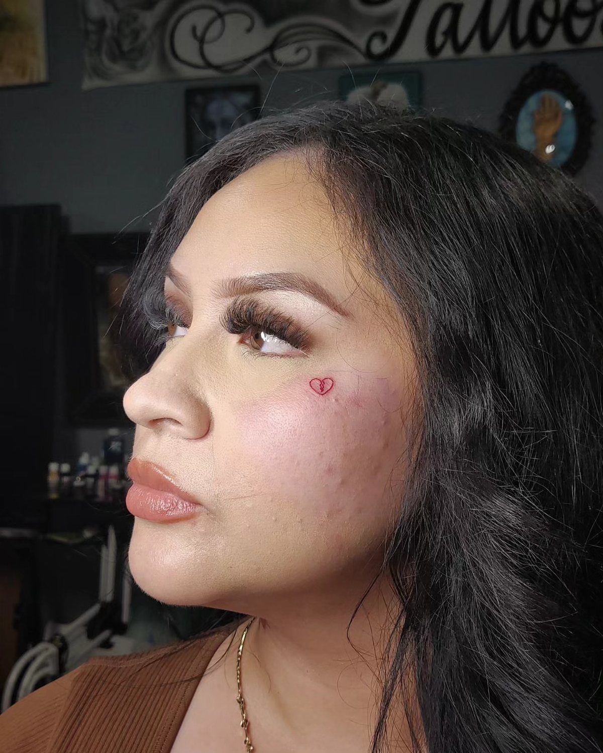 Woman with a small red heart tattoo on her cheekbone