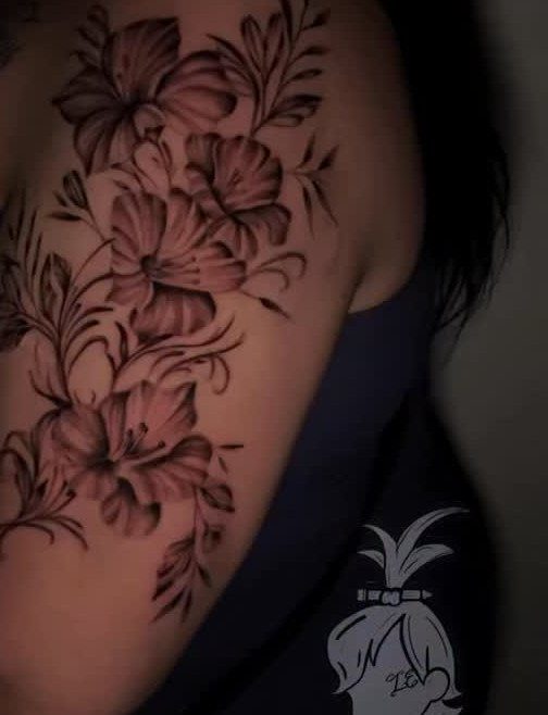 Floral tattoo with blooming flowers and leaves on a person's upper arm.