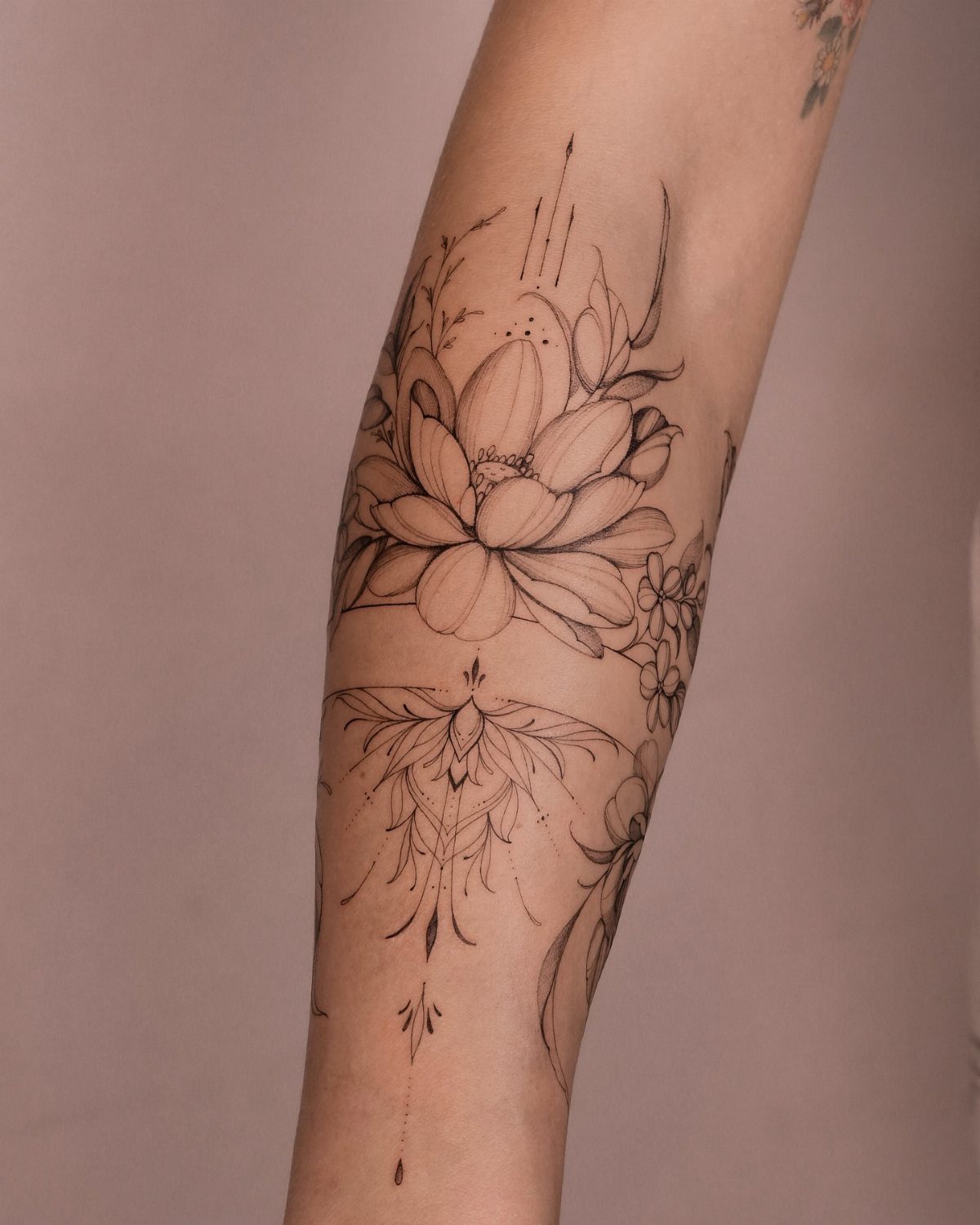 Lotus flower tattoo with ornamental line work on a person's forearm.