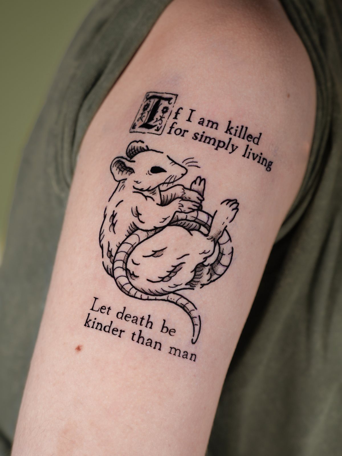 Tattoo on an arm featuring a rat illustration and a poignant written quote.