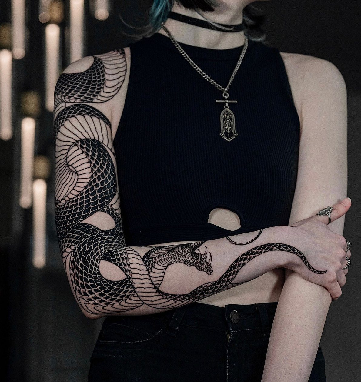 Detailed black ink snake tattoo wrapping around a person's arm and hand.